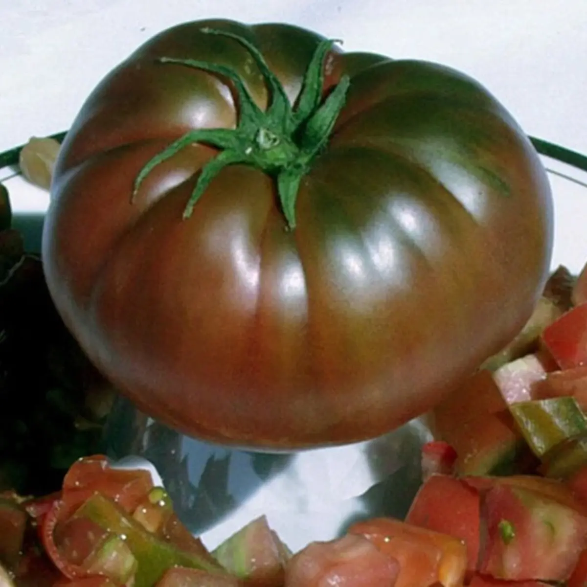 Ripe tomato with green stem on a reflective surface - HarvestNest Seeds